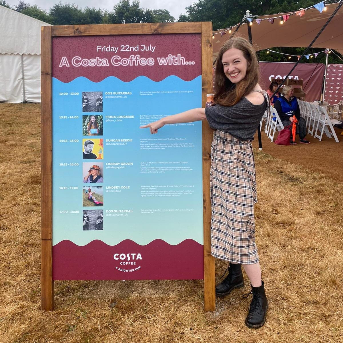 Fiona is pointing to her session on the Costa Coffee Reading Room programme board and grinning